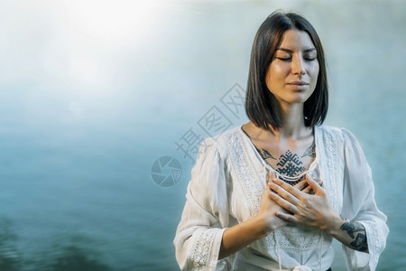 瑜伽后退宁静的年轻女子坐在莲花的位置上静地坐在湖边冥想图片