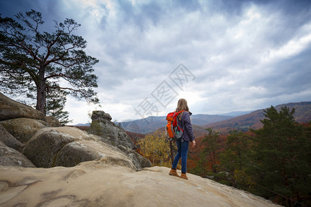 背着包的女孩站在Dovbush岩石上在喀尔巴马人乌克林图片