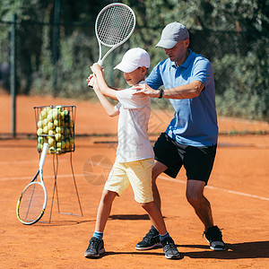 网球教练在粘土场上有年轻才华男孩有网球课背景图片