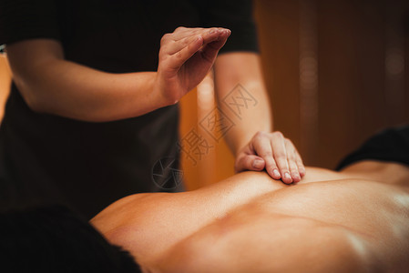 生理治疗师按摩男病人背部肌肉受伤运动害治疗图片