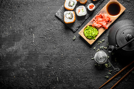 美味的日本寿司卷绿色茶和酱汁黑生锈背景图片