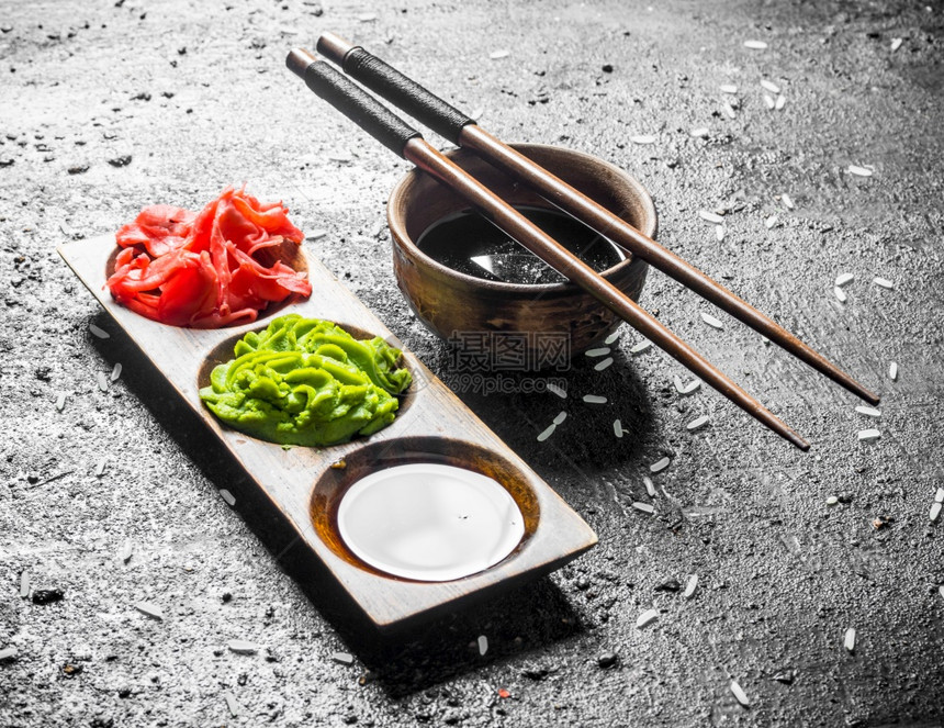 碗里的酱油和寿司用筷子黑色生锈背景的酱油图片