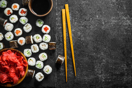 混合的寿司寿司卷在一块石板上面有酱油和姜汁深黑的生锈背景背景