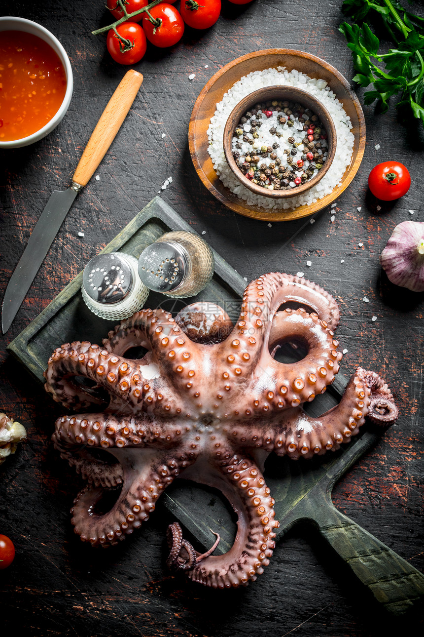 有大蒜和香料的剪切板上章鱼黑暗生锈背景上章鱼带大蒜和香料的剪切板上章鱼图片