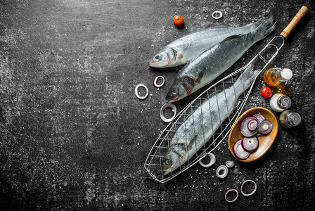 有香料西红柿和洋葱环的生鱼深背景的鱼香料西红柿和洋葱圈的生鱼图片