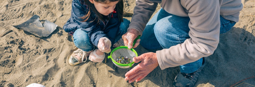 爷和孙女志愿者在海滩上拾取微塑料图片