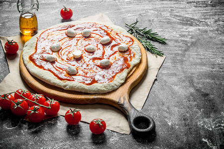 准备披萨面团加番茄糊和马扎里拉生锈背景图片