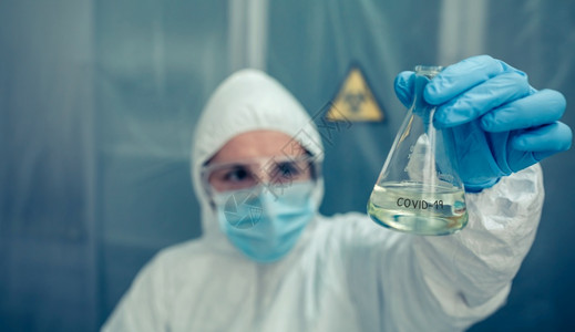 实验室内有细菌保护西装防服的女科学家有选择地关注表的试验管图片