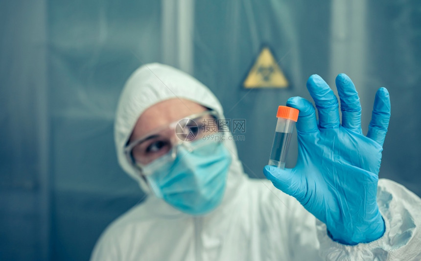 有细菌保护西装的女科学家在实验室监视小瓶图片