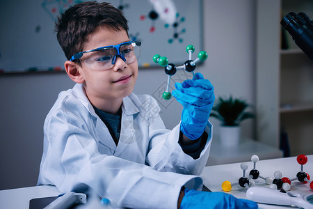 拥有分子模型的可爱男孩在实验室里图片