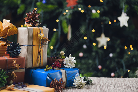 圣诞礼物包装在彩色品纸上圣诞树背景灯光亮度不高圣诞礼物背景图片