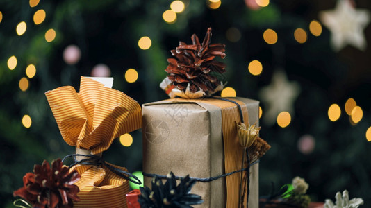 圣诞礼物装在手工制作的盒子和装饰圣诞树上背景有彩色的灯光没有焦点图片