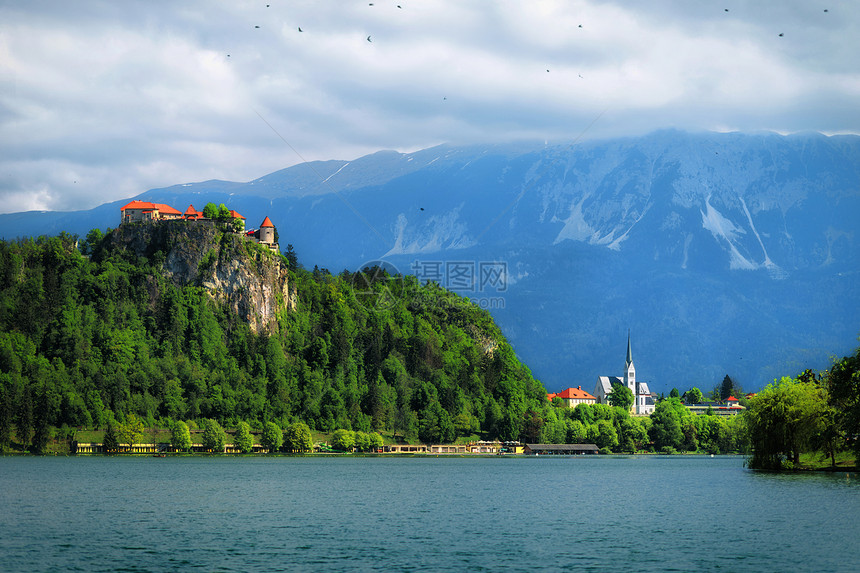 美丽的中世纪城堡在流淌着冰河的湖上与背景中的山峰图片