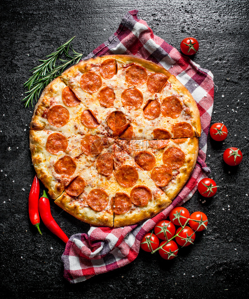 辣椒披萨在餐巾纸上辣椒和西红柿黑色生锈背景图片