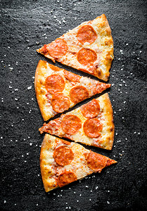 辣椒尼披萨片香肠和奶酪黑色生锈背景图片