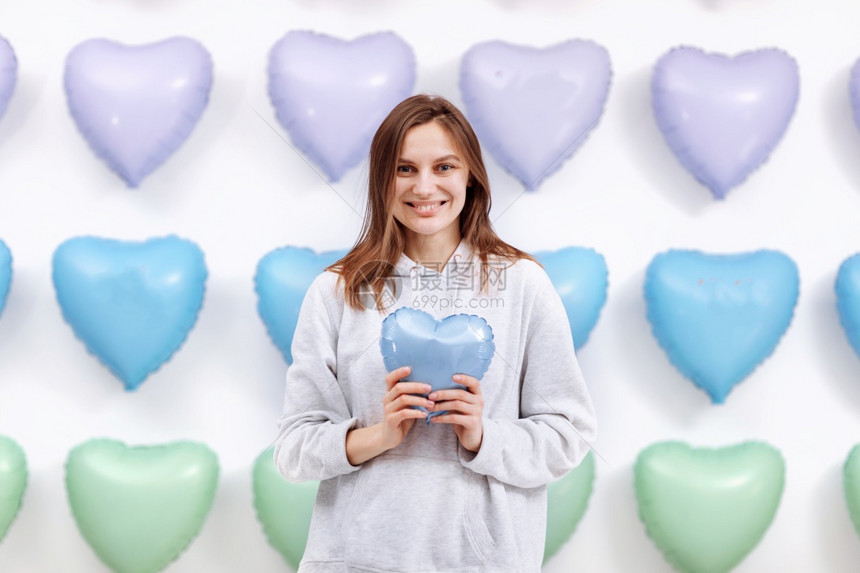 女人把蓝色的气球以心脏形式放在许多心脏背景上情人节选择焦点女人把蓝色的气球放在许多心脏背景上图片