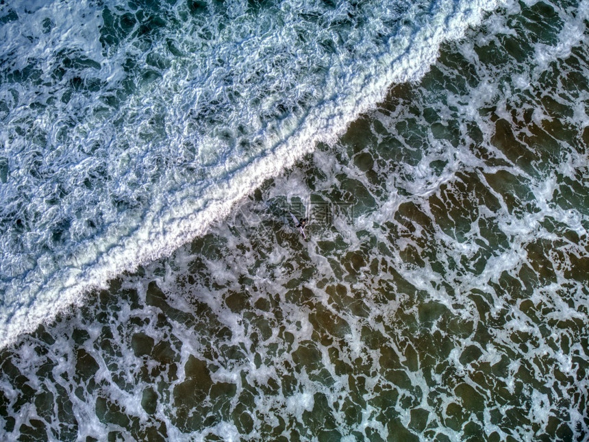 冲浪者进入水面的空中视线与他的冲浪板在海滩上阿斯图里亚西班牙图片