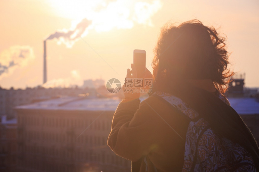 在智能手机圣彼得斯堡拍摄照片的游客女孩图片