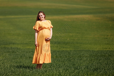 穿着长裙的孕妇在草地里站着图片