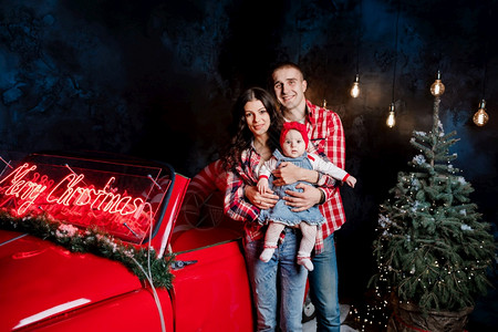 圣诞节夫妇抱着可爱的女儿在汽车前拍照图片