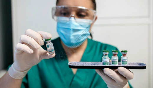 检查科罗纳疫苗小瓶有选择地关注手头和前方小瓶子背景图片