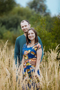 年轻丈夫和妻子在田里抱着草牵手幸福的家庭节快乐图片