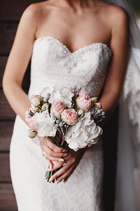 新娘穿着优雅的婚纱盛着一束美丽的花朵和绿色叶子婚礼主题穿着优雅的婚纱新娘拿着一束美丽的花朵和绿色叶子背景图片