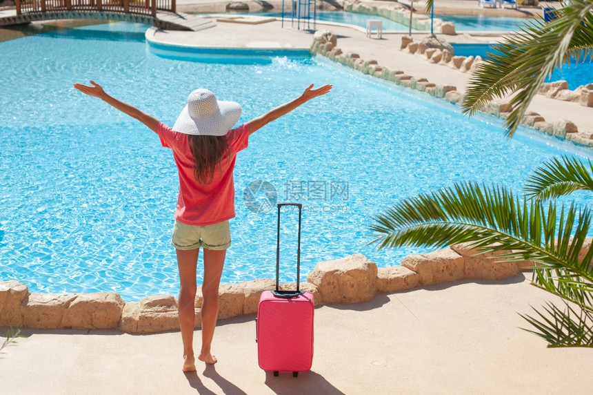 旅行暑假和期概念美丽的妇女用粉色手提箱在旅馆游泳池附近举起手来美丽的妇女用粉色手提箱在旅馆游泳池附近举起手来图片