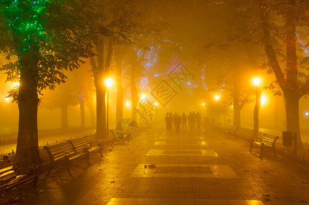 在浓雾的夜中走在市心公园小巷的人图片