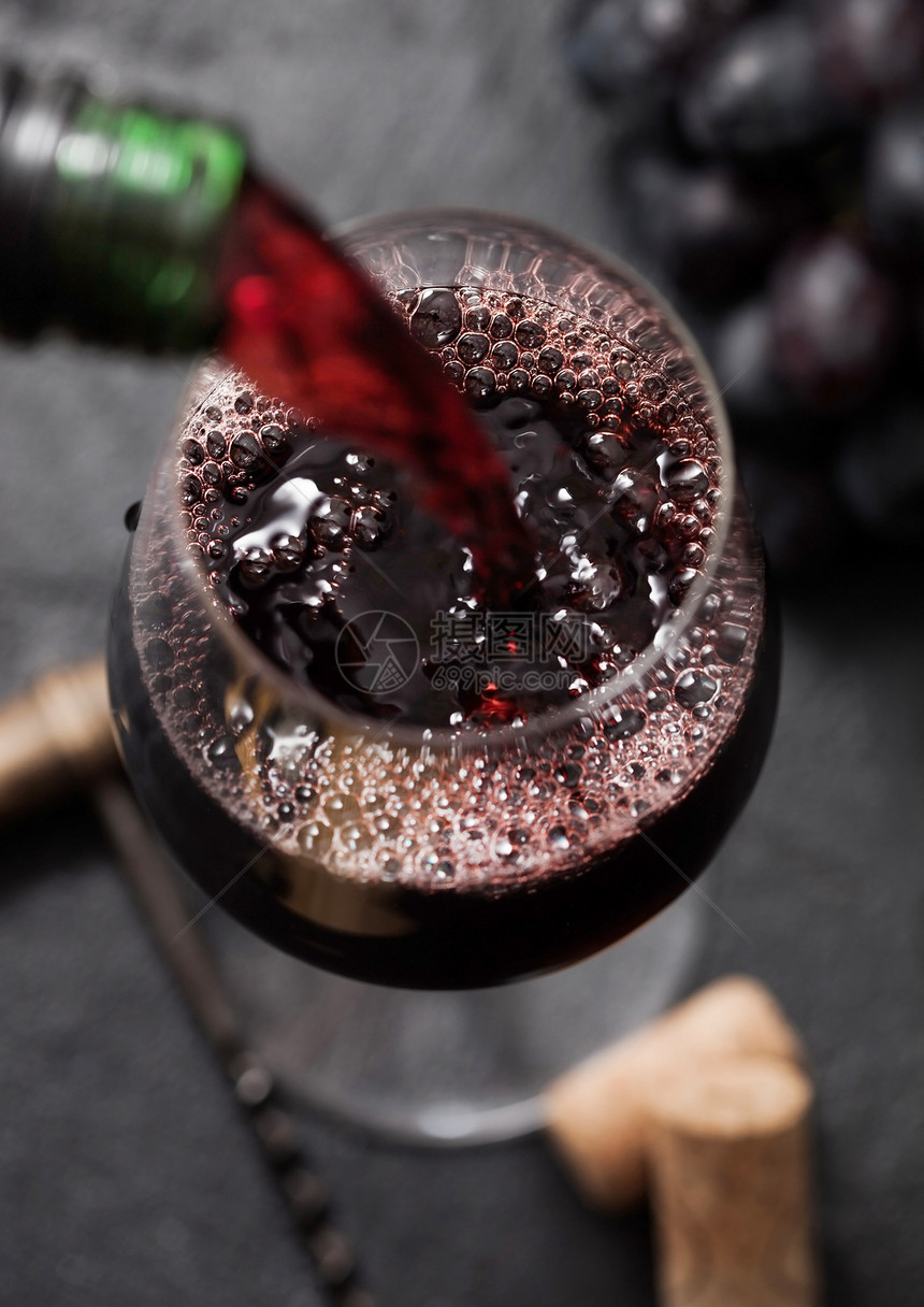 将红酒从瓶子倒到杯上以黑色背景装有瓶子和最高视图图片