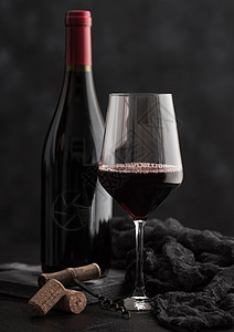 和玻璃瓶红葡萄酒装有软木和古老的黑色底有深布图片