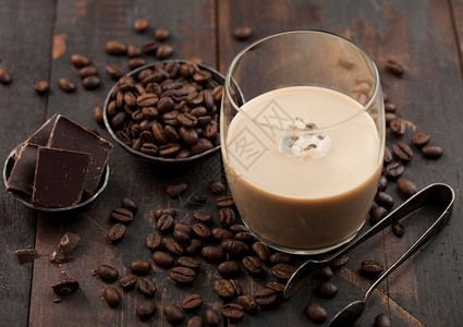 黑色木质背景的钢碗里有冰块咖啡豆和深色巧克力图片