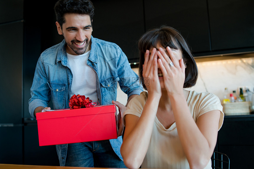 年轻人的肖像用礼物盒给他的女朋友一个惊喜庆祝和情人节概念男用礼物给他女朋友一个惊喜图片