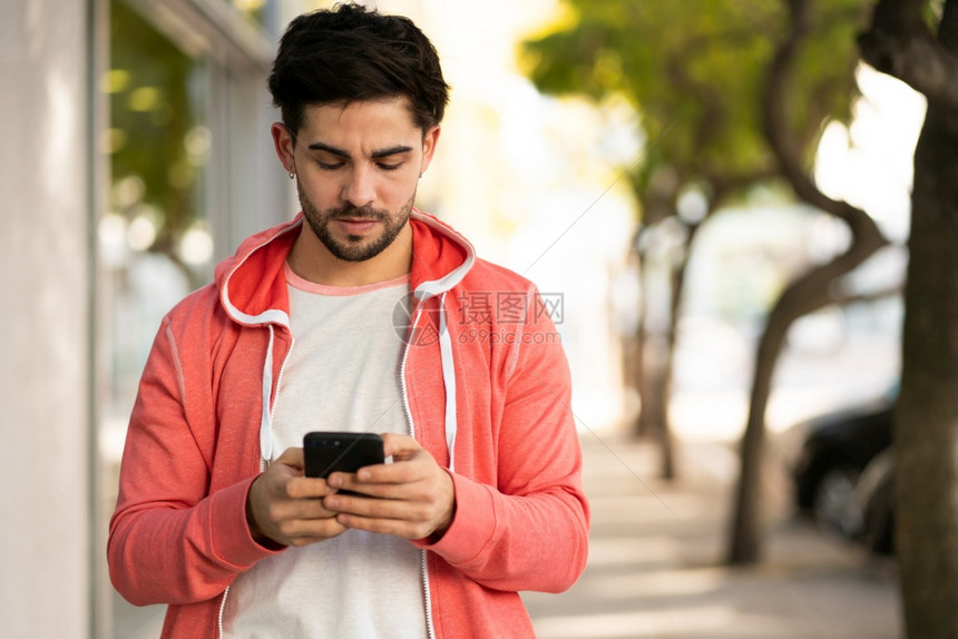 年轻人在街上户外散步时使用手机的肖像图片