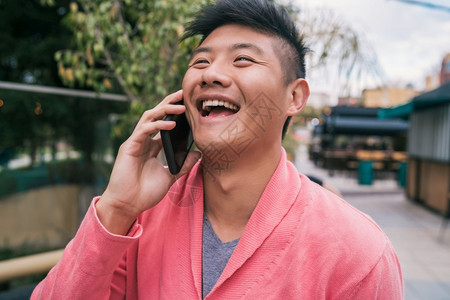 年轻亚洲男子在街上户外电话交谈的肖像图片