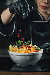 厨师的手在素食餐厅装配沙拉上掉落的石榴餐厅厨师配上石榴种子的沙拉图片