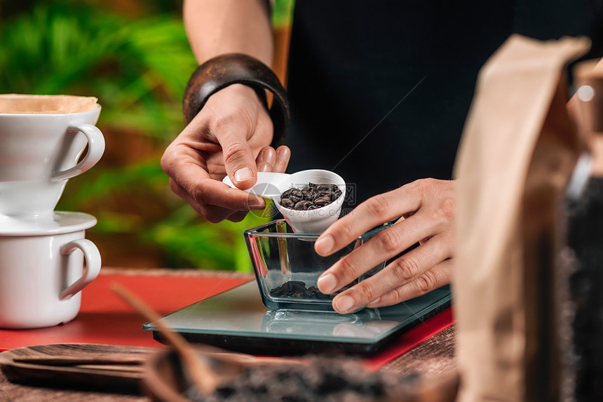 咖啡过滤器女家在泡滴之前以数字规模对咖啡豆进行称重图片