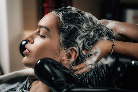 理发师对女人施洗水美容院的头发洗背景