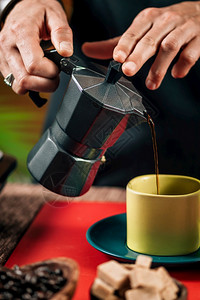 咖啡从一个黑茶壶倒入黄咖啡杯图片