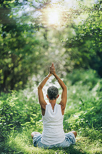 无法辨认的心思清醒女在一片平淡的绿林中冥想练习技巧帮助她的中心并找到内在平衡坐地上双手举起头顶默想以平衡为中心图片