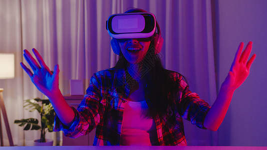 Asia女士戴着快乐的游戏头盔拥有可穿戴的乐趣体验穿戴虚拟提升现实数字创新科技年一的夜宴节庆祝活动快乐时刻在家客厅举行晚宴庆祝活背景图片