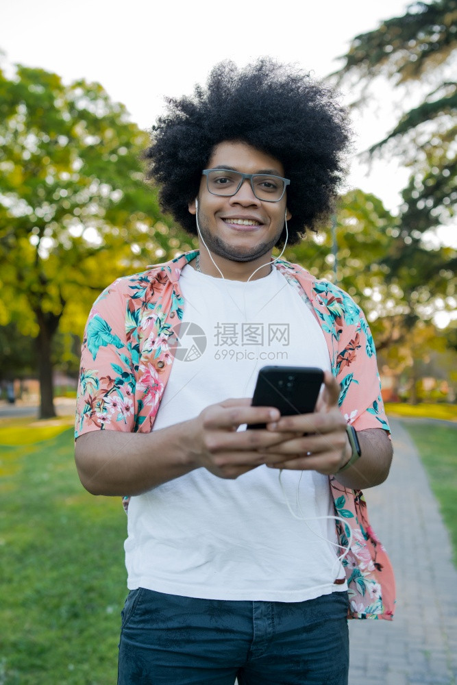 年轻拉丁男子在街上露天使用手机的肖像图片