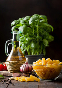 玻璃碗中的新鲜面粉配有巴西尔植物油和红柿木制桌底有大蒜和胡椒图片