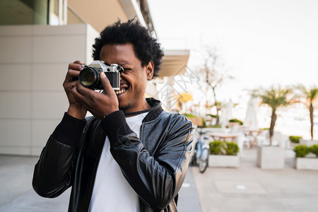 afro观光客在街上走户外时用相机拍照的肖像图片