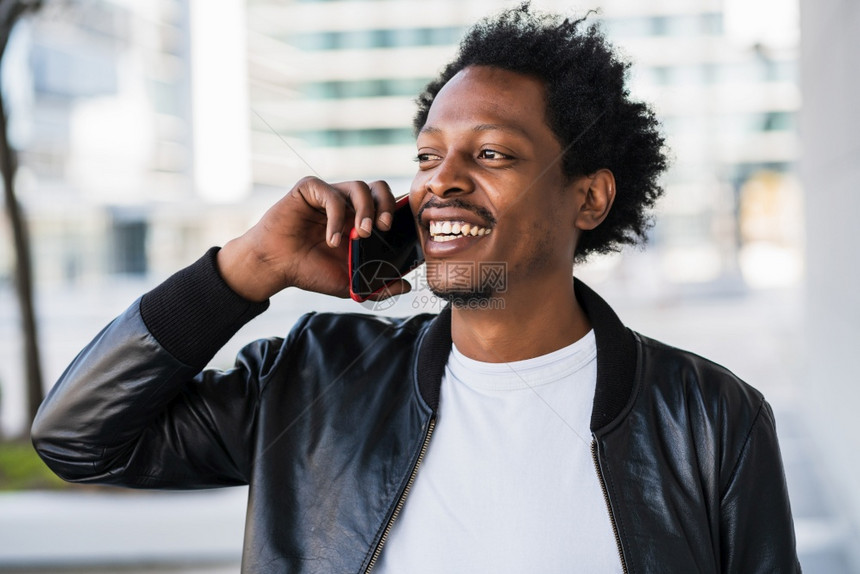站在街上户外散步时在电话上说的afro男人肖像城市概念图片