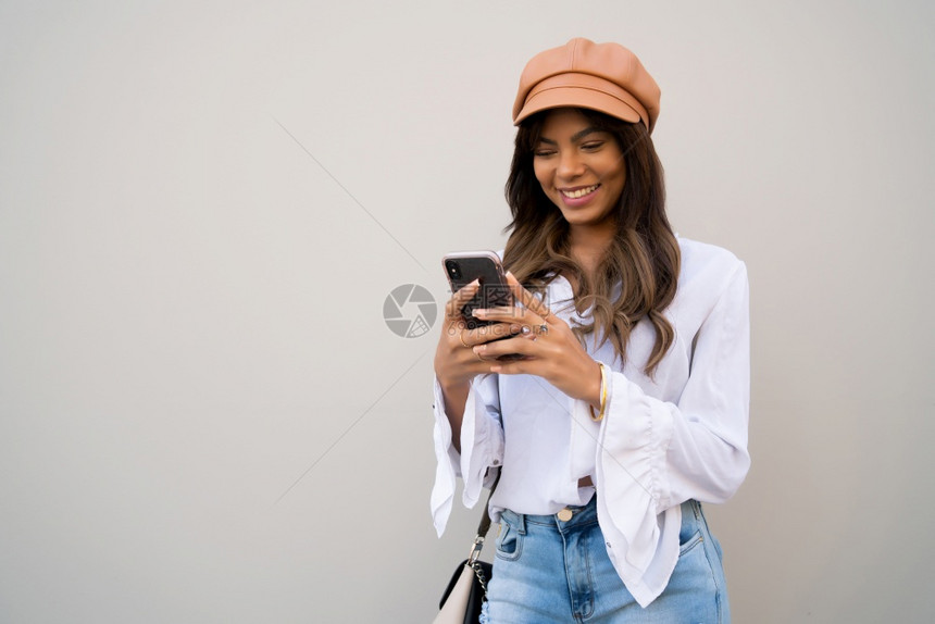 年轻女在街上户外站立时使用手机的肖像图片