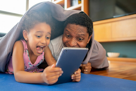 女儿和父亲在一起玩得开心在家里使用数字平板电脑单亲概念图片