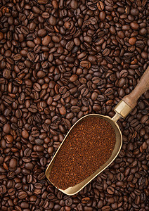 咖啡豆背景的旧钢勺中新鲜烤咖啡粉背景图片