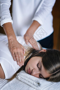 女抗逆转录治疗师的垂直形象肩上握着病人的膀和转移能量平的少女闭着眼睛躺减轻压力和放松的替代治疗概念背景