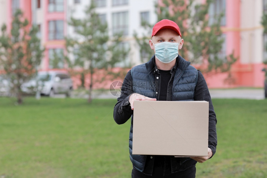 身着红色帽子的送货员面部医疗具装着空的纸箱室外服务科罗纳在线购物模拟送货员装着红色帽子面部医疗具装着空的纸箱室外模拟图片